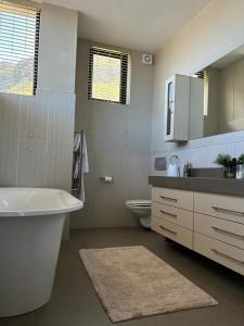 a bathroom with a tub and a sink and a toilet at House Vos in Hermanus