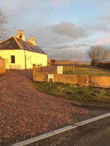 a white house on the side of a road at Dunes View, Cottage1, Dunnetbay accommodation in Castletown