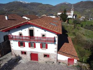 an old building with red doors and a roof at Apartamentos en Baztan HIRU KABI, HIGA in Lecároz