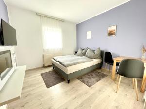 Schlafzimmer mit einem Bett, einem Tisch und einem TV in der Unterkunft SmartRooms24 in Villach