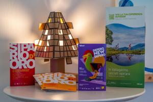 a table with books and a christmas tree on it at Ostello Città di Rovereto in Rovereto