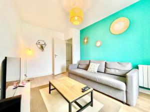 - un salon avec un canapé et un mur bleu dans l'établissement Brest - Le Gestin - Appartements - Lumineux - Tout Confort - Fibre Internet, à Brest