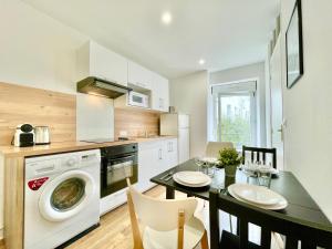 une cuisine avec un lave-linge et une table avec des chaises dans l'établissement Brest - Le Gestin - Appartements - Lumineux - Tout Confort - Fibre Internet, à Brest