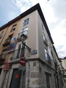 ein hohes weißes Gebäude mit Fenstern und einem Straßenschild in der Unterkunft Estudio con encanto en Casco Antiguo de Burgos P2 in Burgos