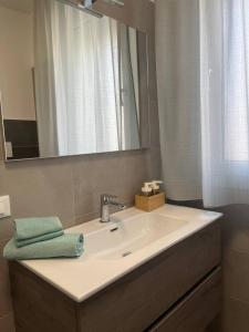 un lavandino in bagno con specchio e asciugamano verde di "La Terrazza di Via Roma" Delta del Po - Private Parking a Porto Viro