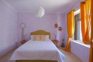 a bedroom with a bed and two windows with orange curtains at FULLHOUSE Moudros in Moúdhros