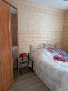 a bedroom with a bed and a wooden wall at MAISON OSSATURE BOIS in La Bourboule