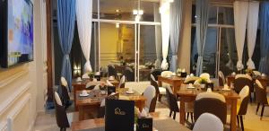 un ristorante con tavoli e sedie in legno e una grande finestra di Eastern City Hotel a Dodoma