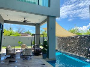 un patio con piscina y pared de piedra en Molly Luxury Private Pool Bungalow茉莉的家豪华私人泳池别墅 en Pantai Cenang
