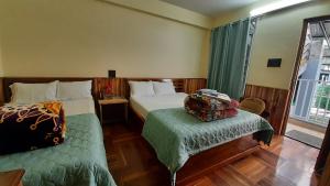 a bedroom with two beds and a chair and a window at The Brick House Stay in Kalimpong