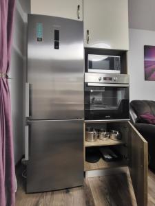 a stainless steel refrigerator in a kitchen with a microwave at Subcetate Residence in Bistriţa