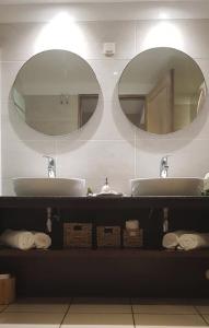a bathroom with two sinks and two mirrors at PALMAÉ de Boucan Canot T2 St-Gilles A 200M de la plage in Saint-Gilles les Bains