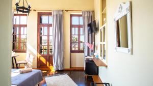 sala de estar con cama, TV y ventanas en Ruby 'n Emerald studio's en Rethymno