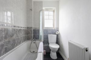 a bathroom with a toilet and a tub with a window at Beautiful Comfortable Double Room in Thamesmead