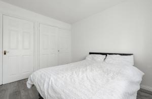 a white bedroom with a white bed with a black headboard at Beautiful Comfortable Double Room in Thamesmead