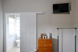 a bathroom with a toilet and a television and a door at Tates Hotel Windsor in Windsor