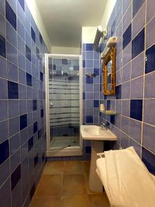 La salle de bains est pourvue de carrelage bleu, d'un lavabo et d'une douche. dans l'établissement Hotel François 1Er, à Manosque