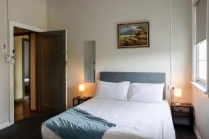 a bedroom with a bed with two lamps and a picture on the wall at Tates Hotel Windsor in Windsor