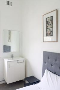 ein weißes Schlafzimmer mit einem Bett und einem Spiegel in der Unterkunft Tates Hotel Windsor in Windsor