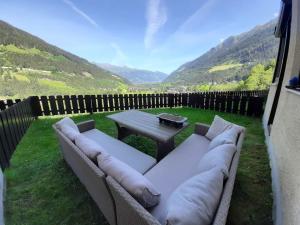a couch with pillows sitting in a yard with a table at Cozy apartment w a view & own garden in Bad Gastein