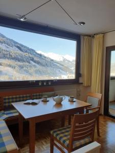 een eetkamer met een tafel en een groot raam bij Cozy apartment w a view & own garden in Bad Gastein