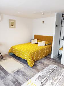 - une chambre avec un lit et une couverture jaune dans l'établissement Les Gones en Vendée, à Saint-Gervais