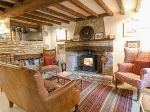 a living room with a stone fireplace and chairs at Brooklands in Chedworth
