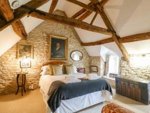 um quarto com uma cama grande numa parede de pedra em Brooklands em Chedworth