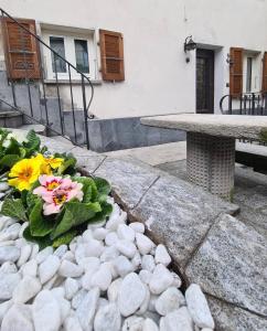 Casa Rosina - Una caramella, nel nucleo, ai piedi della Verzasca- في غوردولا: طاولة وزهور في حديقة بها صخور