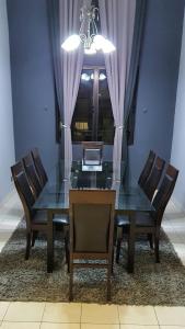 uma mesa de jantar e cadeiras com uma mesa de vidro e uma janela em Luxury & Complete 3 Bedroom Penthouse em Shah Alam