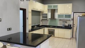 cocina con armarios blancos y encimera negra en Luxury & Complete 3 Bedroom Penthouse, en Shah Alam
