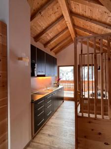 d'une cuisine avec des armoires noires et un plafond en bois. dans l'établissement Lüch dl Finatzer, à San Martino in Badia