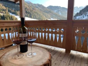 een tafel met twee glazen wijn op een balkon bij Lüch dl Finatzer in San Martino in Badia
