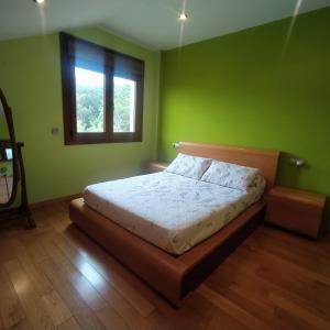 Un dormitorio con una cama con paredes verdes y una ventana en A de Bego, en Mougás