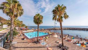 a group of people sitting around a swimming pool with palm trees at Giesta Flower by Madeira Holiday Rentals in Ribeira Brava