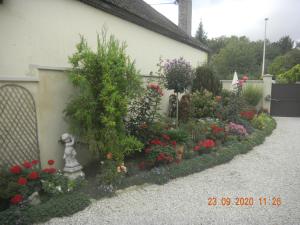 a garden with flowers and a statue next to a building at La Merlette89 in Lailly