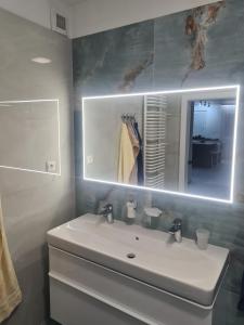 a bathroom with a white sink and a mirror at Apartmán Belezza - priamo v centre in Liptovský Mikuláš