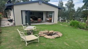 un patio trasero con 2 sillas y una hoguera en Sunset View Self catering Cottage, en Underberg