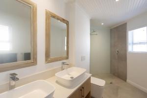 un bagno bianco con lavandino e specchio di Simply Stunning a Cape St Francis Altre 65 foto