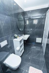 ein Badezimmer mit einem WC, einem Waschbecken und einem Spiegel in der Unterkunft Hotel Viroi in Vlorë
