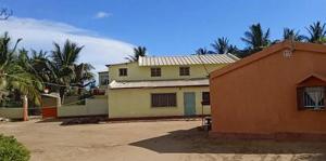 dom siedzący obok budynku z palmami w obiekcie TULEAR APPARTEMENTS CHAMBRES VILLAs w mieście Toliara