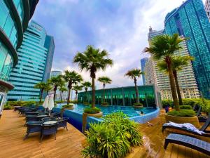 een zwembad in een stad met palmbomen en banken bij Vortex suites near by KLCC in Kuala Lumpur