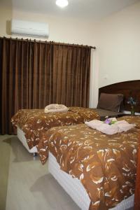1 dormitorio con 2 camas y edredón marrón en Baraka Al Aqaba Hotel Suites, en Áqaba