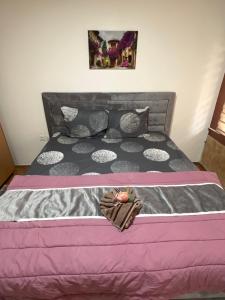 a bed with a pink and gray comforter at ALOHA apartment in Novi Pazar