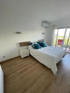 a white bedroom with a large bed with blue pillows at Beta's Beach in Blanes