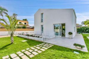 a white house with a garden and a lawn at Domus Maulli - Villa sul mare in Marina di Ragusa