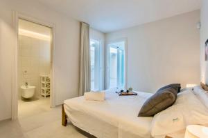 a white bedroom with a large bed and a bathroom at Domus Maulli - Villa sul mare in Marina di Ragusa