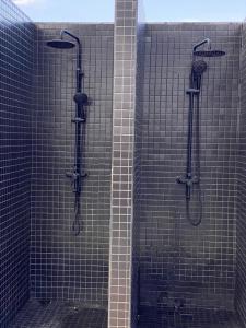a bathroom with a shower with black tiled walls at PARANAIS APARTMENT 2 in Nairobi +5 photos