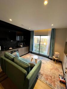 a living room with a green couch and a kitchen at PARANAIS APARTMENT 2 in Nairobi
