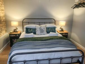 a bedroom with a large bed with two lamps at The Street Cottage in Uley